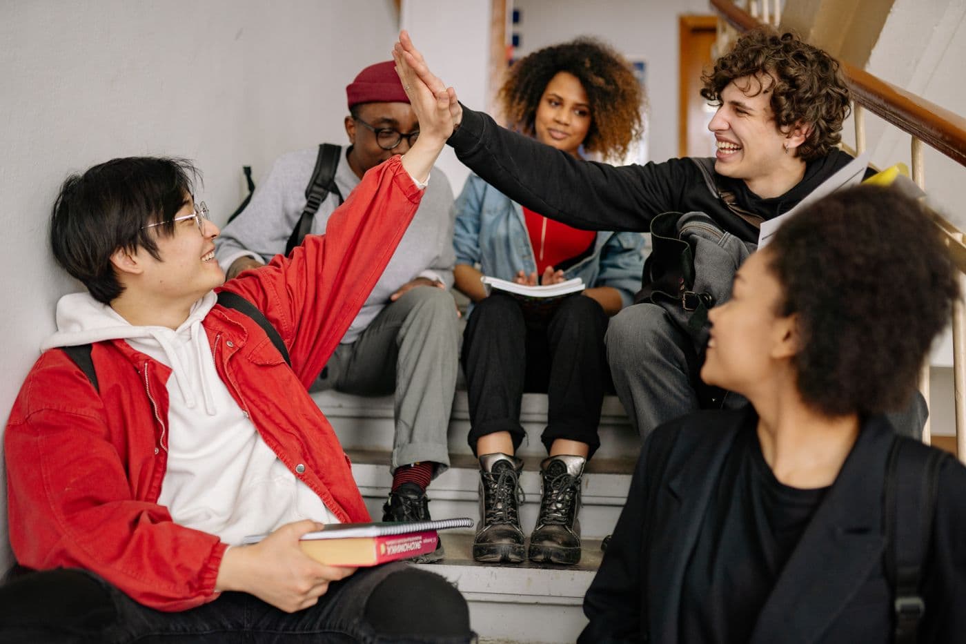 Students on a school staircase sharing a high five.